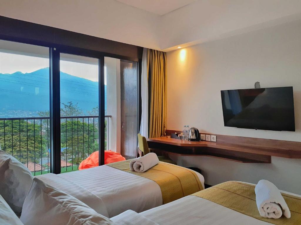 Kamar hotel dengan balkon menghadap panorama pegunungan Kota Batu
